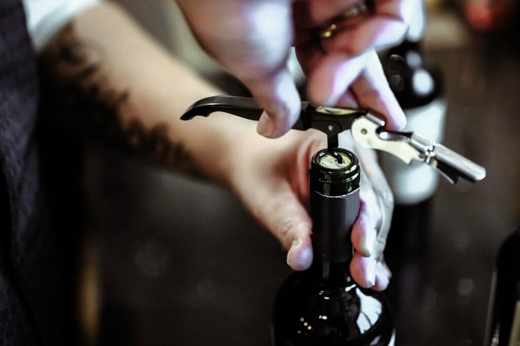 Sommelier opening a bottle of wine with a wine key.