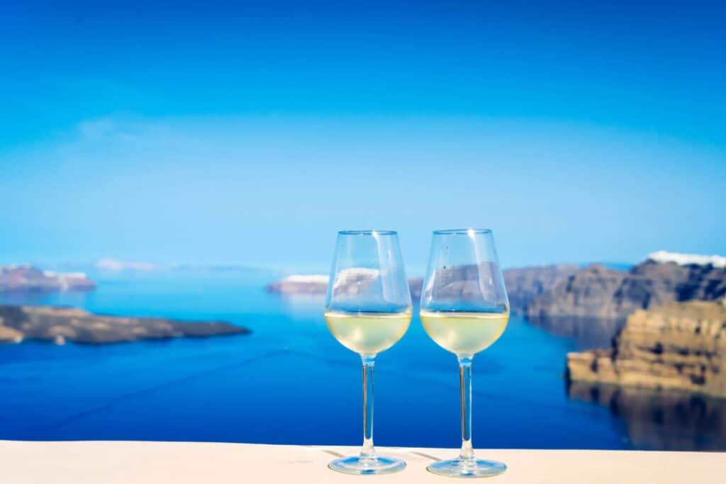 Two glasses of white wine overlooking the sea in Santorini.