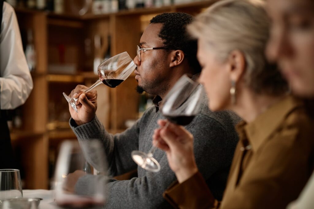 A man and woman smelling red wine during a wine tasting.