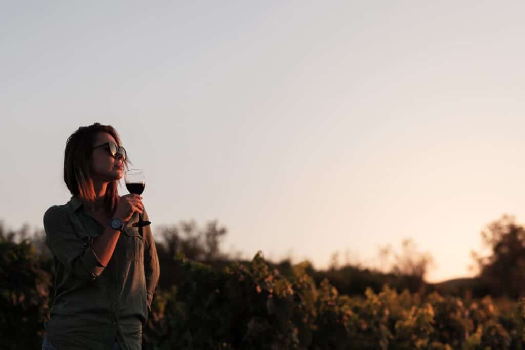 Woman drinking wine in vineyard at sunset in Bordeaux France wine tasting tour