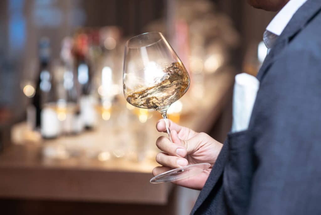 Man swirling white wine in a glass during wine tasting.